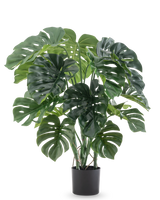 Die Kunstpflanze Monstera 90 cm hat große, gespaltene grüne Blätter und wird in einem schwarzen Topf vor einem schlichten weißen Hintergrund geliefert.