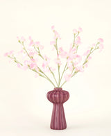 Der Seiden-Kunstblumenstrauß Erbse in Hellrosa mit mehreren hellrosa Erbsenstielen in einer gerippten burgunderfarbenen Vase steht vor einem hellen Hintergrund – ideal für jedes Kunstblumen-Interieur.