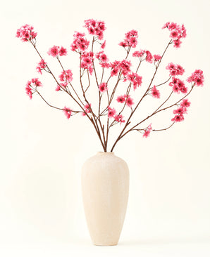 Der künstliche Blumenstrauß aus Seide, Kirschblüten-Fuchsia, 114 cm, verleiht Ihrem Interieur mit seinen markanten Zweigen und fuchsiafarbenen Blüten, die wunderschön in einer beigen Keramikvase vor einem schlichten, cremefarbenen Hintergrund zur Geltung kommen, einen lebendigen Farbtupfer.