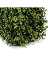 Nahaufnahme von dichten, grünen Blättern an der künstlichen Buchsbaumhecke UV 70x20x25 cm, die eine üppige künstliche Hecke mit kleinen, runden Blättern in verschiedenen Farbtönen bildet. Unten links ist eine dicke, quadratische Ecke sichtbar.