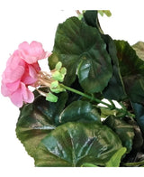 Eine Nahaufnahme der künstlichen Geranie 40 cm rosa, mit mehreren grünen Blättern vor weißem Hintergrund.