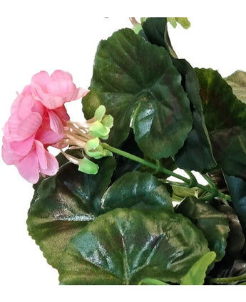 Eine Nahaufnahme der künstlichen Geranie 40 cm rosa, mit mehreren grünen Blättern vor weißem Hintergrund.