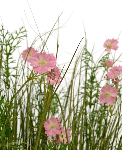 Der 90 cm große, feuerhemmende Kunstrasen-Zwiebelgrastopf mit rosa Gesangsblumen hat rosa Blüten mit einem hellgrünen Herzen, die zwischen hohem, dünnem Gras und üppigen Blattpflanzen blühen, alles vor einem weißen Hintergrund.