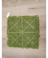 Das künstliche Haag Nordic Moss 50x50 cm UV ist eine grüne Kunstrasenmatte mit einer sichtbaren Kunststoffgitterrückseite, ideal für luxuriöse Innenräume oder die Schaffung einer grünen Wand. Es steht auf einem hellen Holzboden mit einem kleinen weißen Etikett in einer Ecke.