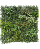 Die künstliche Hecke Prestige 100 x 100 cm UV ist eine quadratische Platte aus künstlichem grünem Blattwerk mit gemischten Blattpflanzen, Farnen, verschiedenen Texturen und Grüntönen sowie Büscheln kleiner weißer und roter Blüten. Der Hintergrund ist weiß.